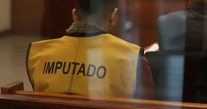 Persona con chaleco de imputado sentada en una sala de audiencias